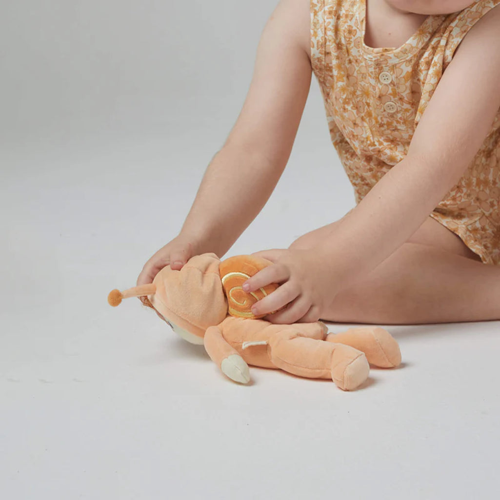 child holding olli ella orange Scottie snail face down in white room 