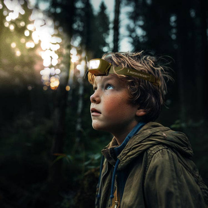Child wearing rechargeable headlight during outdoor adventure outside in forest at night