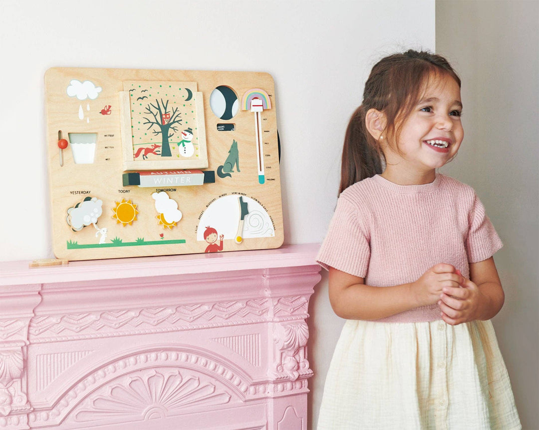 Weather Watch displayed on a mantel while a girl in a pink dress smiles beside it