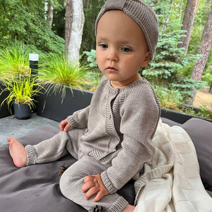 Baby sitting outdoors in a taupe ALIAP Merino Wool Plain Knit Baby Bodysuit and matching headband, cozy fall baby clothes