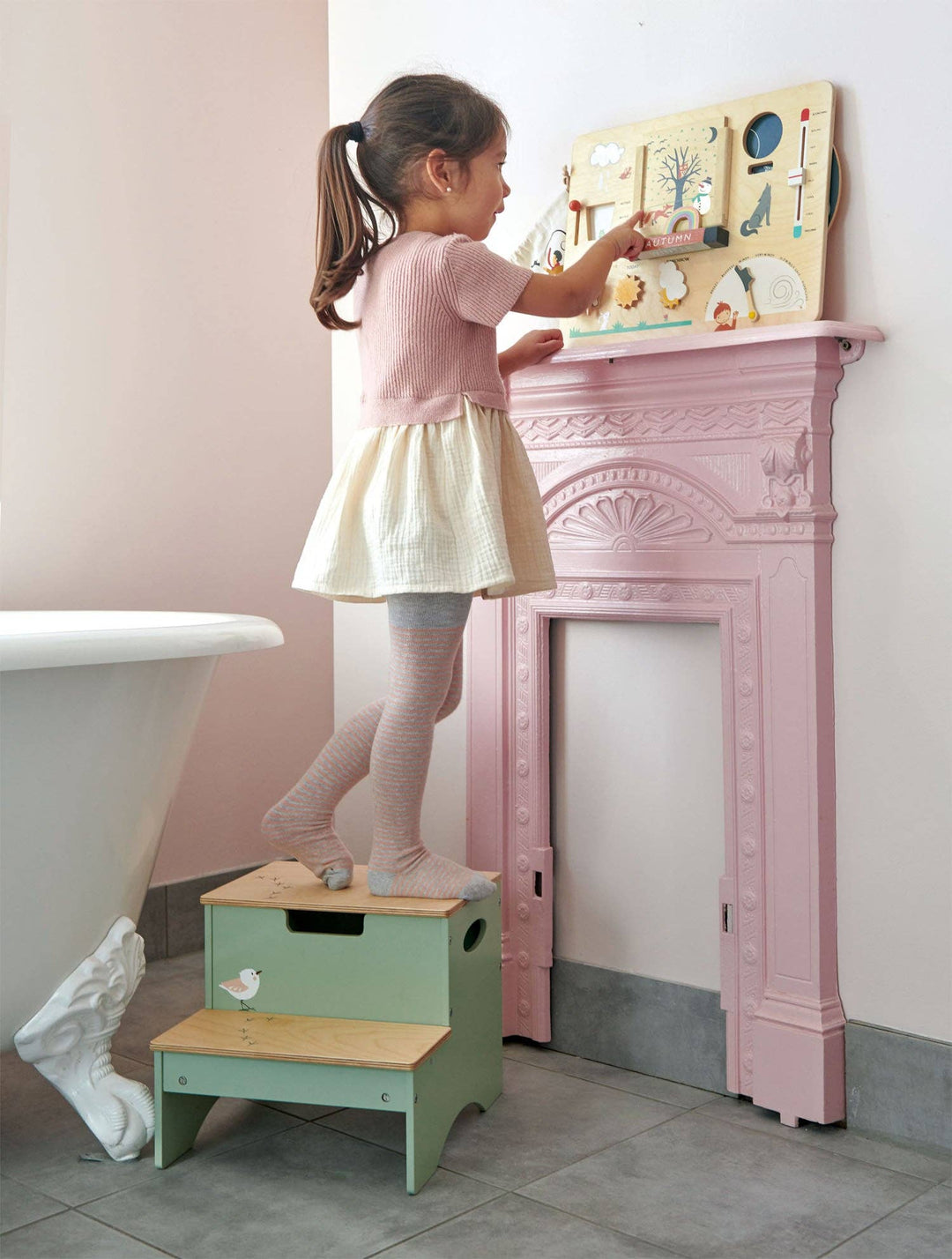 A little girl climbs a step stool to reach her Tender Leaf Toys Weather Watch display