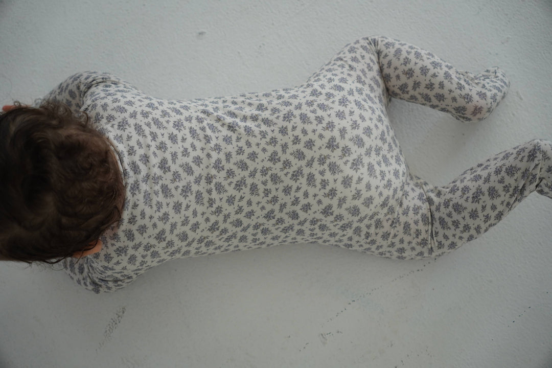 Top view of baby wearing Little Threads floral bamboo footie, soft baby pajamas designed for mobility, cozy sleep, and everyday comfort