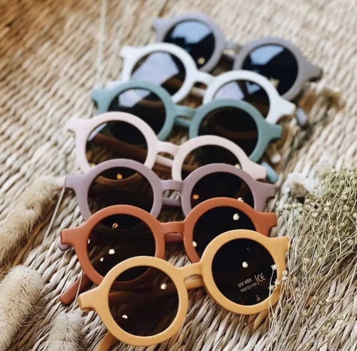 line of boho and babe retro 60s inspired baby and kid sunglasses in bright colors on woven basket 