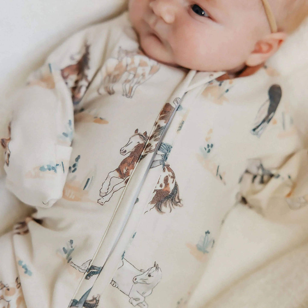 Baby in Copper Pearl Montana footie lying in bassinet, cozy newborn sleepwear for naps, bedtime, and everyday comfort