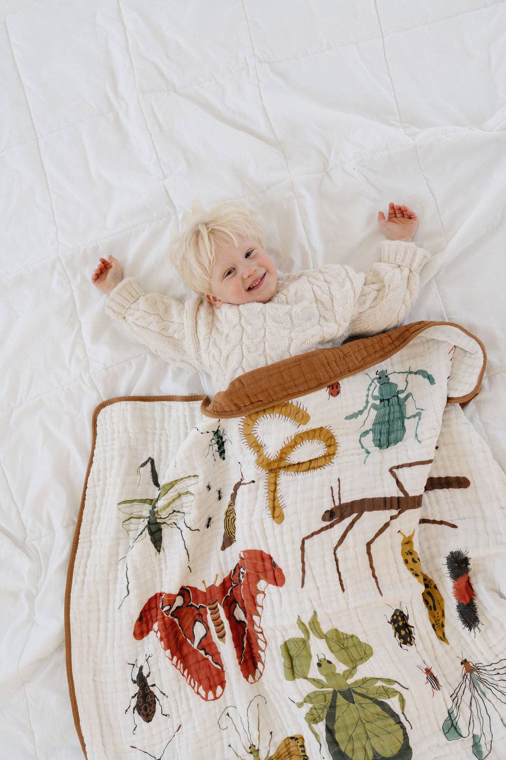 Clementine Kids Cutie Crawlies Quilt wrapped in soft muslin blankets, perfect for baby snuggles and nursery style.