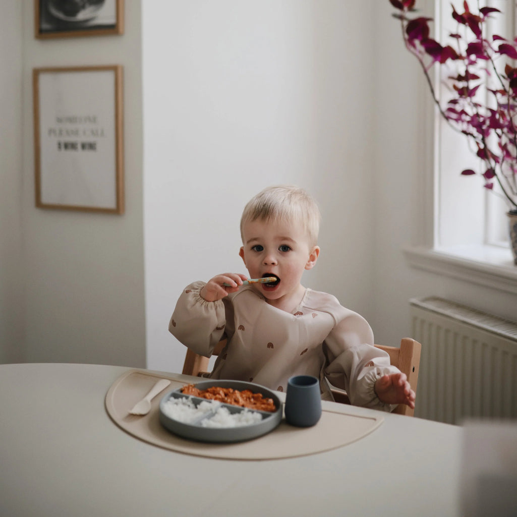 toddler using mushie first feeding spoon