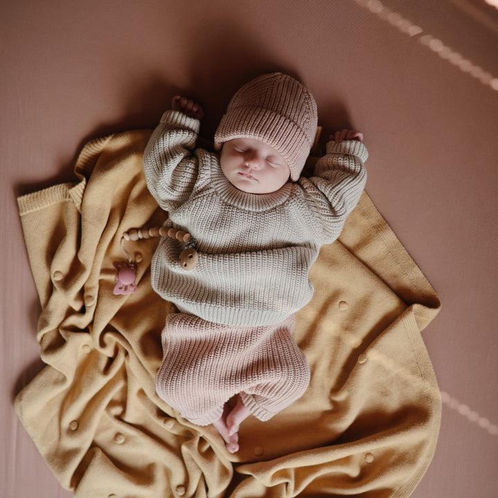 Baby sleeping soundly on a soft natural stretchy bassinet sheet providing a cozy environment