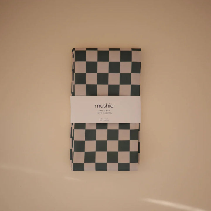 The olive check Mushie Splat Mat is a stylish silicone placemat protecting surfaces from spills and messes.