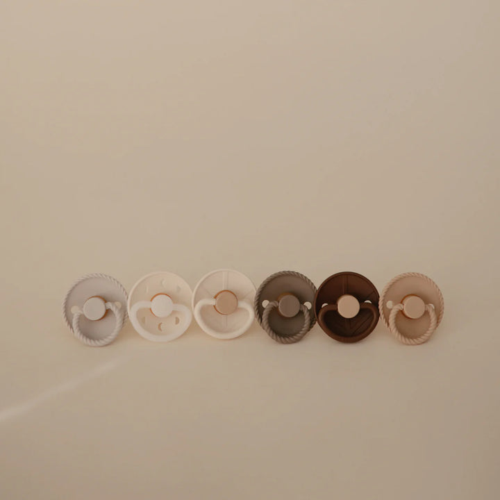 FRIGG Earthy Wonder rubber pacifier flat lay - six natural latex baby pacifiers on clean neutral surface