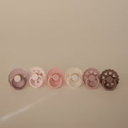 FRIGG Blooming Love silicone pacifier 6-pack flat lay - blush-toned orthodontic newborn pacifiers on white