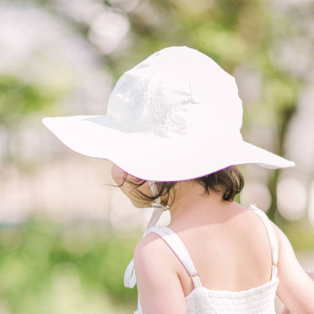 child playing outside while being protected by huggalugs sun safe white sun hat 