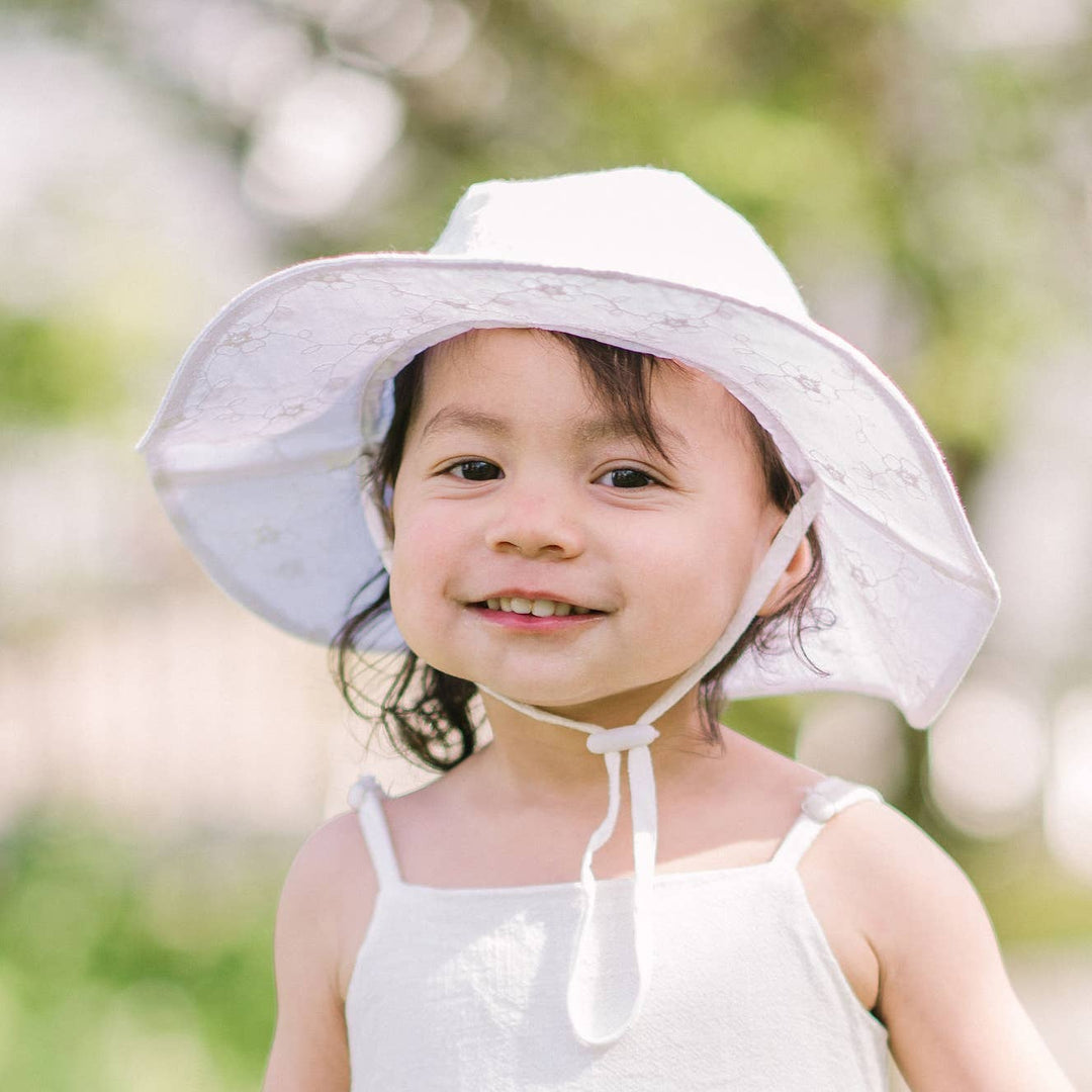 toddler wearing white floral embroidered upf 50 plus hugga luggs sun hat 