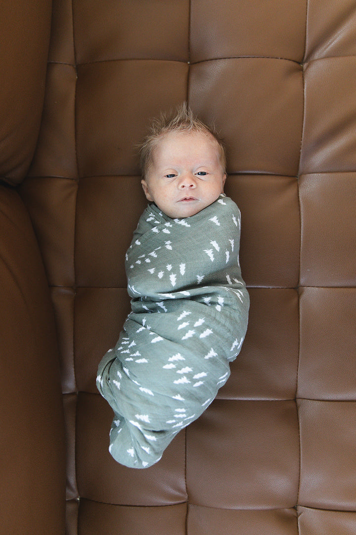 Shop swaddle blankets at Mebie Baby now, the Pines Muslin Swaddle Blanket styled with matching nursery decor.