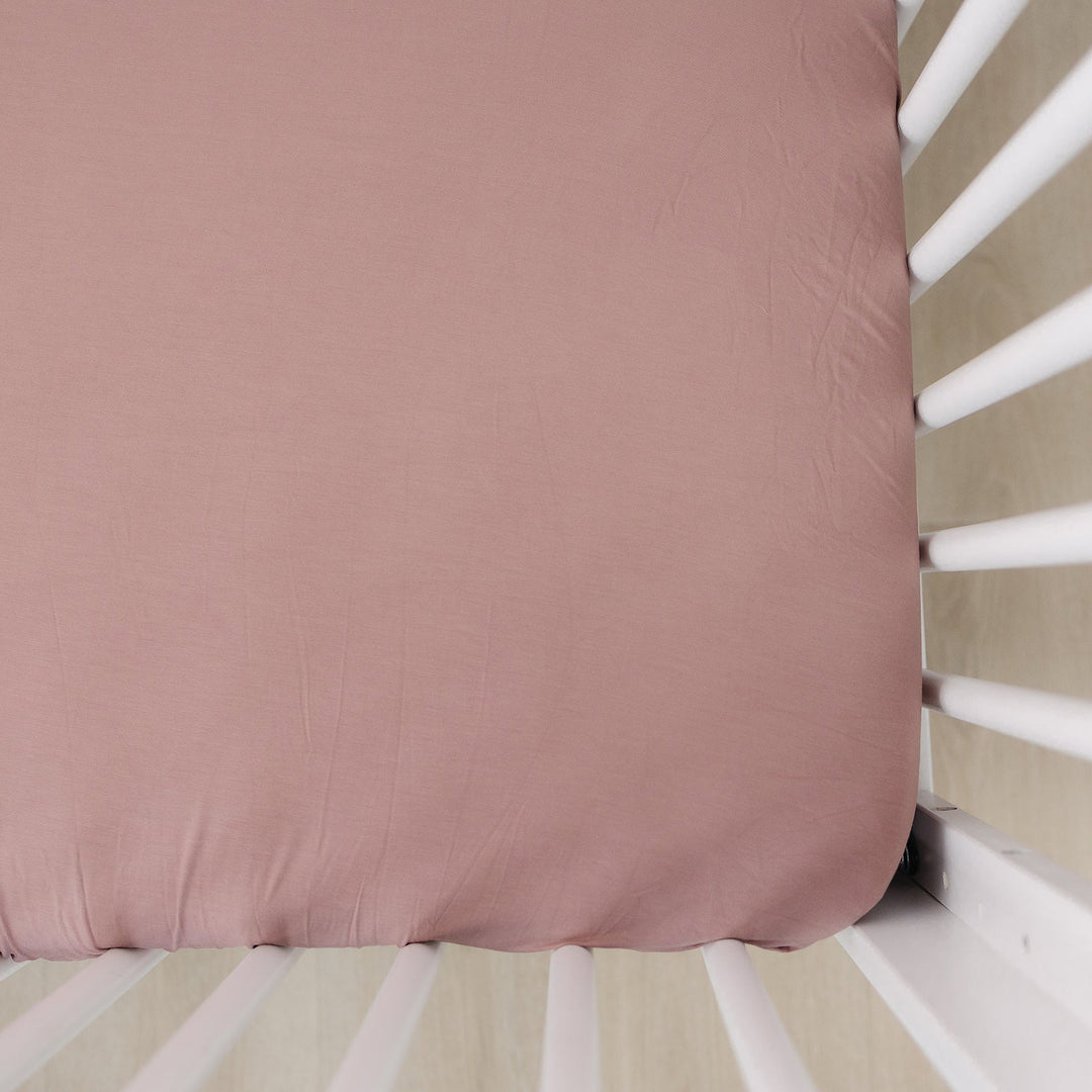 Dusty Rose Bamboo Stretch Crib Sheet by Mebie Baby, fitted on a crib mattress.