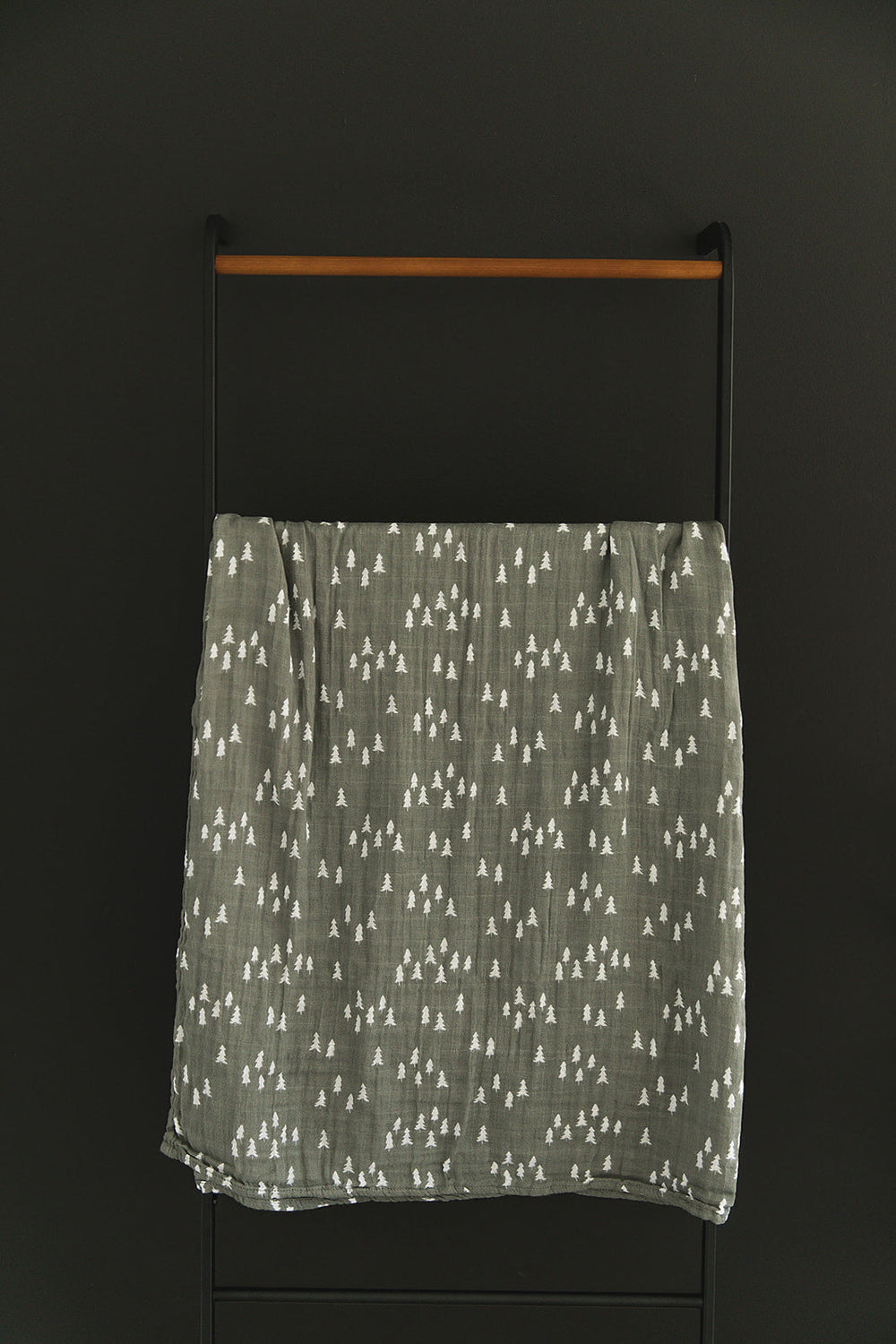 Wrapped around a sleeping newborn, the Pines Muslin Swaddle Blanket from Mebie Baby.