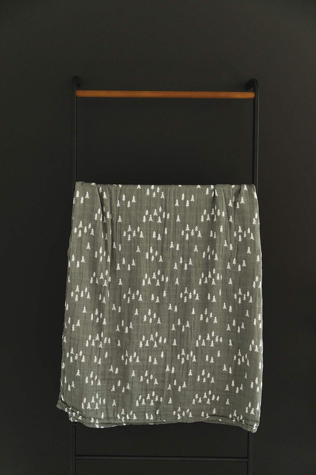 Wrapped around a sleeping newborn, the Pines Muslin Swaddle Blanket from Mebie Baby.