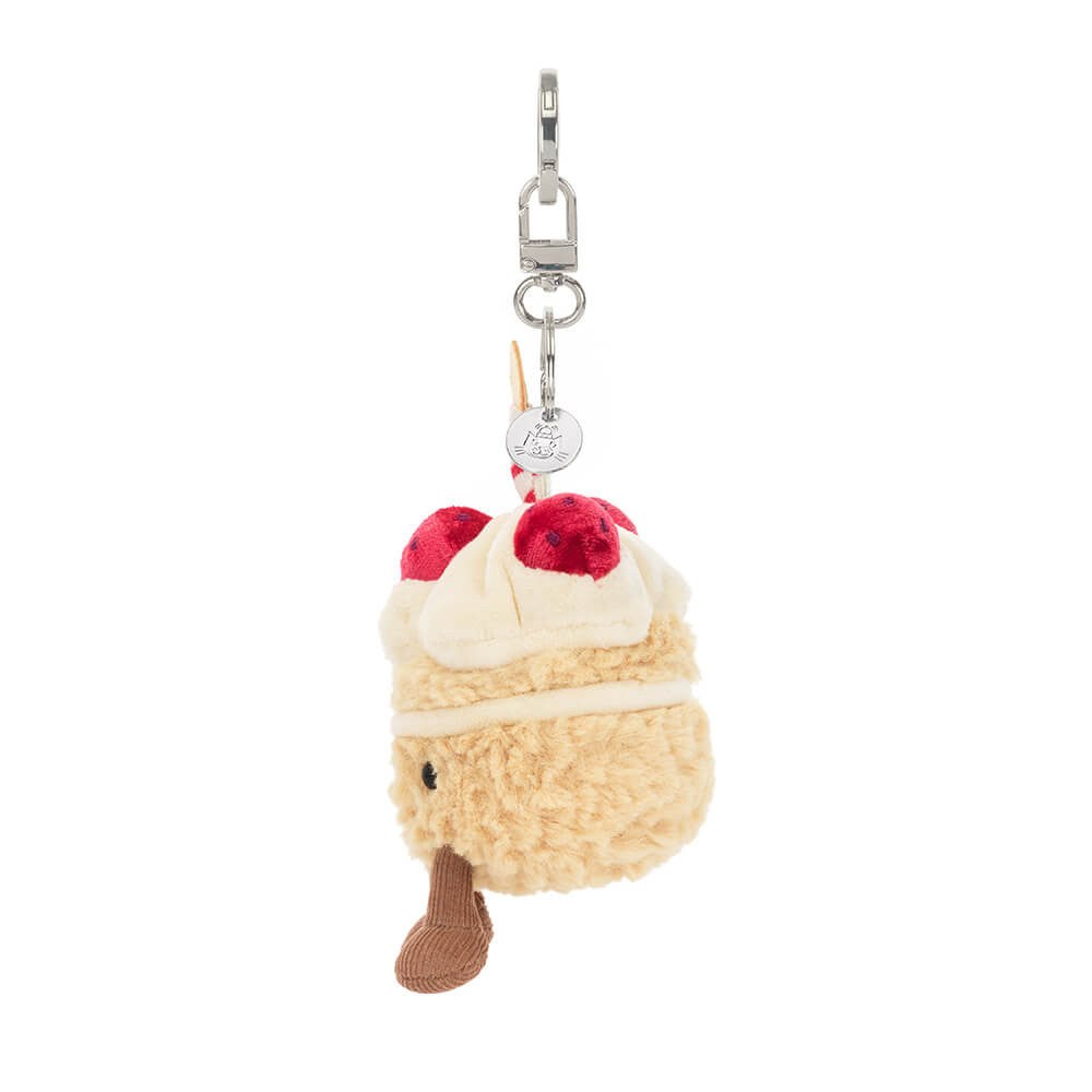 Side view: Amuseables Birthday Cake keychain by Jellycat on silver clip, plush bag charm for backpacks