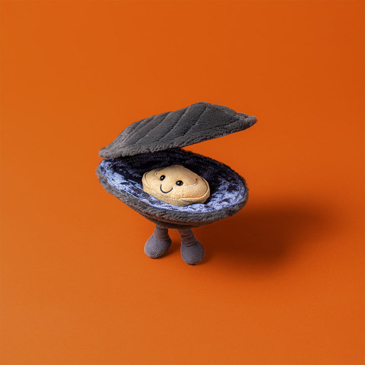 Jellycat Michelle Mussel stuffed animal plush toy ocean food, standing on an orange background. 