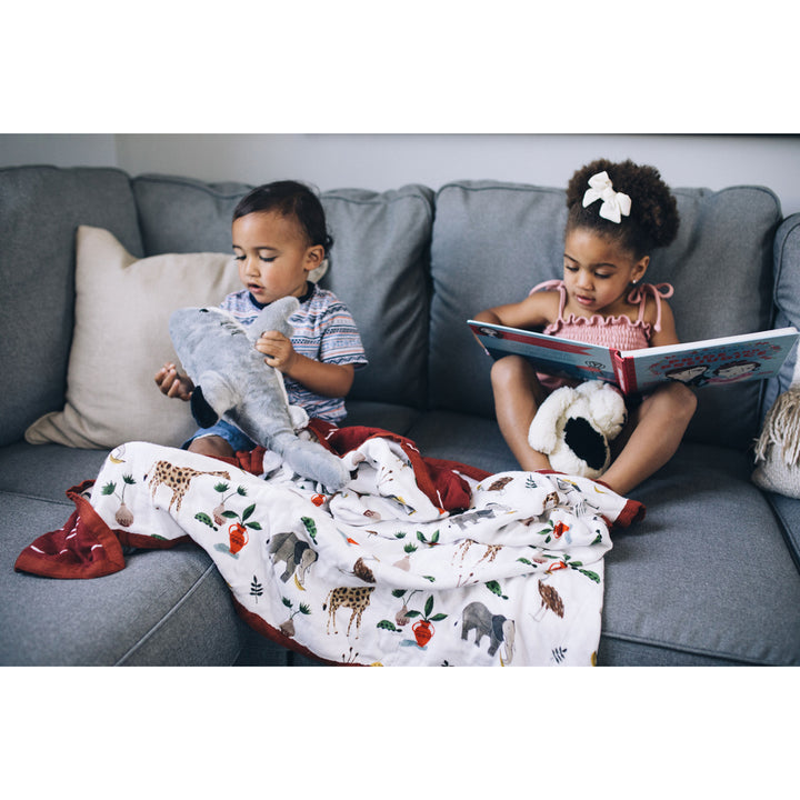 Kids enjoy storytime wrapped in the Little Unicorn Deluxe Muslin Quilt - Safari Social baby blanket.