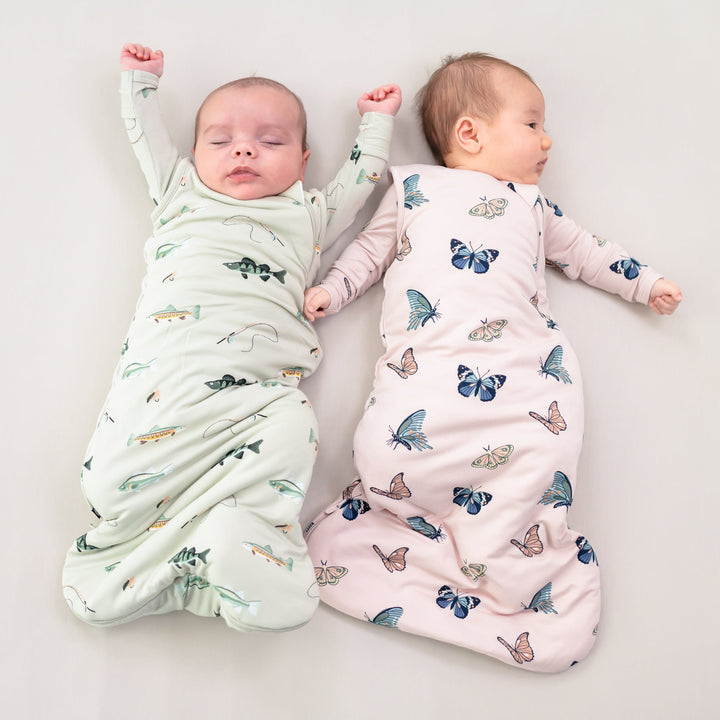 Babies wearing Kyte Baby sleep bags TOG 1.0 in Fishing and Blush Butterfly prints