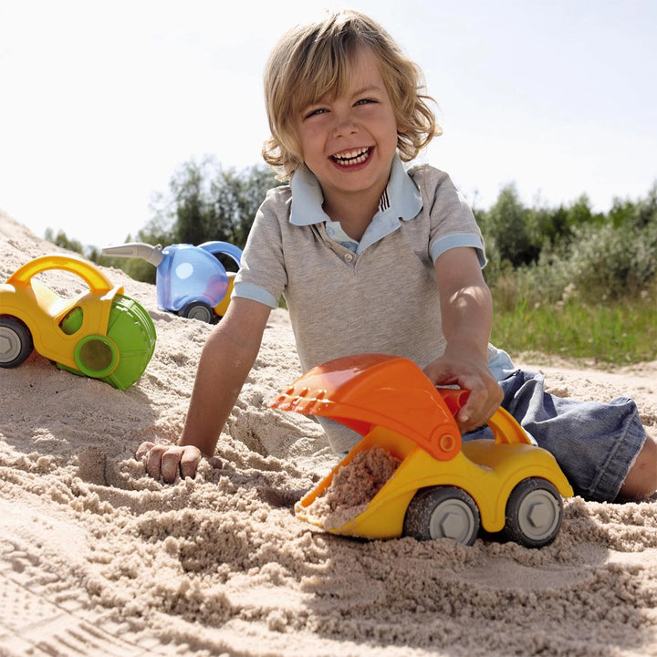 Kid enjoying the beach with a vibrant orange and yellow sand excavator toy.