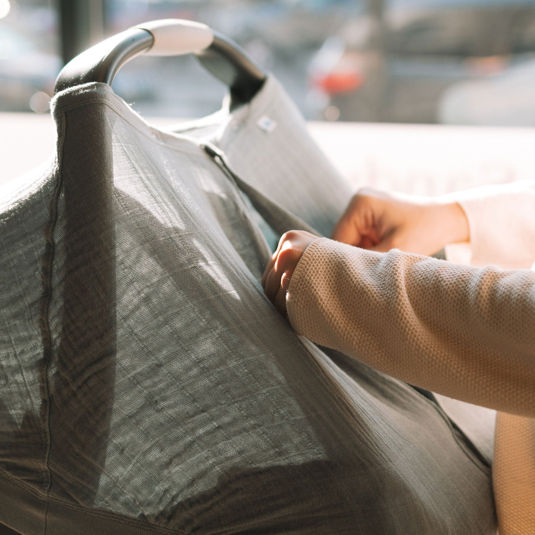 Lifestyle image showing the Little Unicorn Cotton Muslin Car Seat Canopy - Sea in use, bringing comfort and style to every baby car seat.