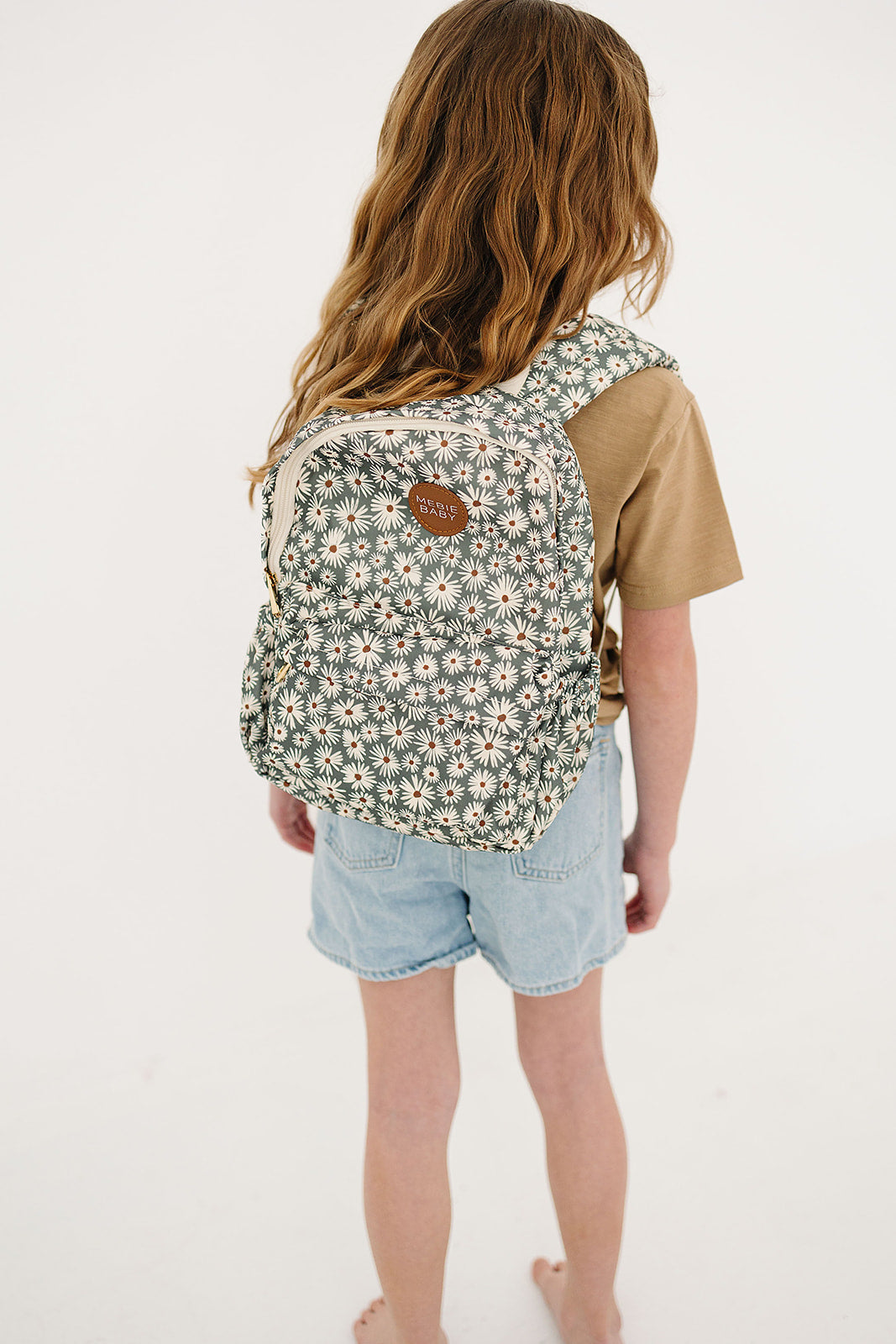 Mebie Baby Green Daisy Mini Backpack modeled on a child, a durable mini backpack ideal for school or outings