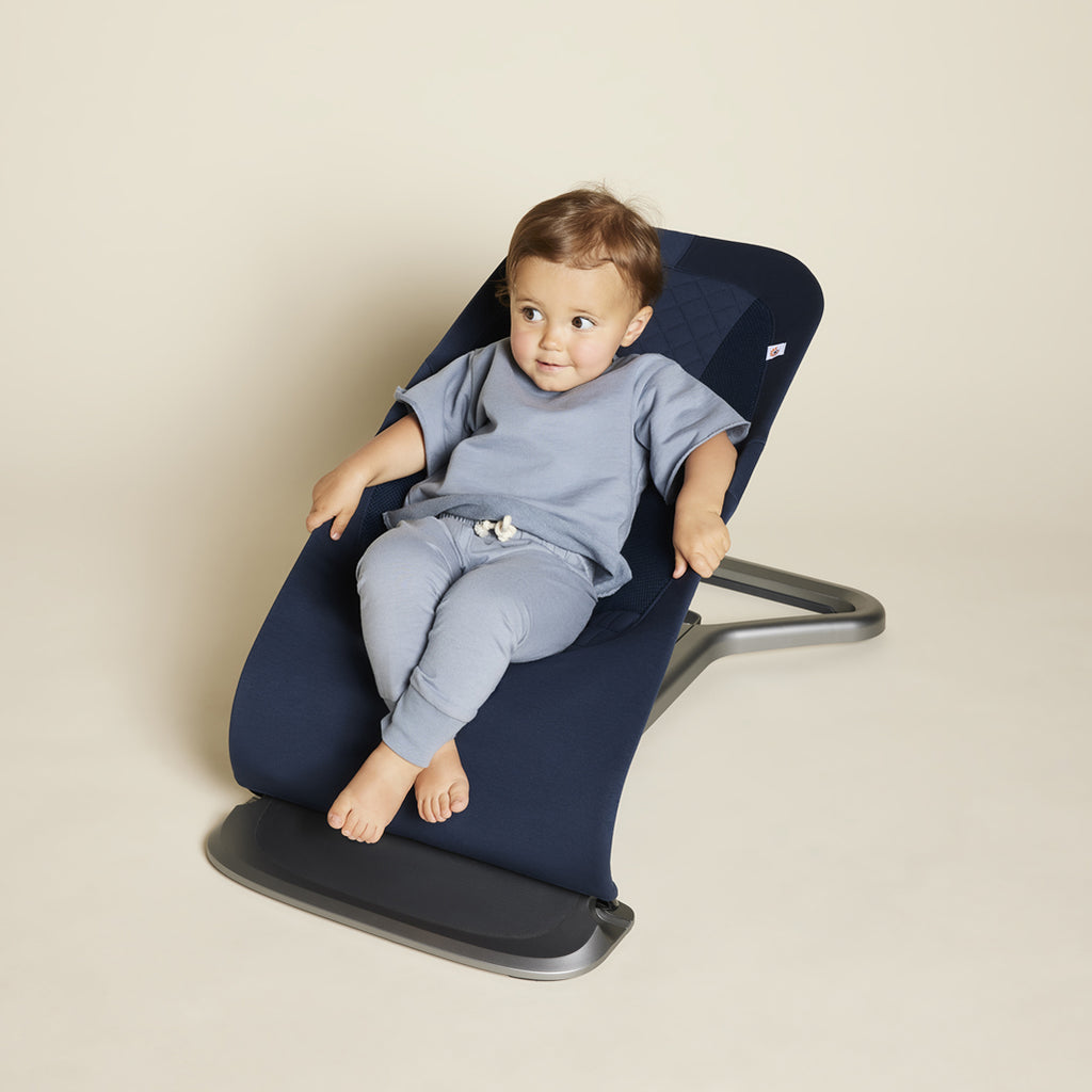 Toddler sitting in a midnight blue Ergo baby bouncer