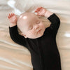 Sleepy baby wearing the comfy Kyte Baby Romper in the color Midnight.