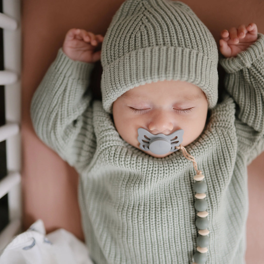 infant with blue pacifier in mouth