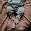 infant in fleece booties mushie