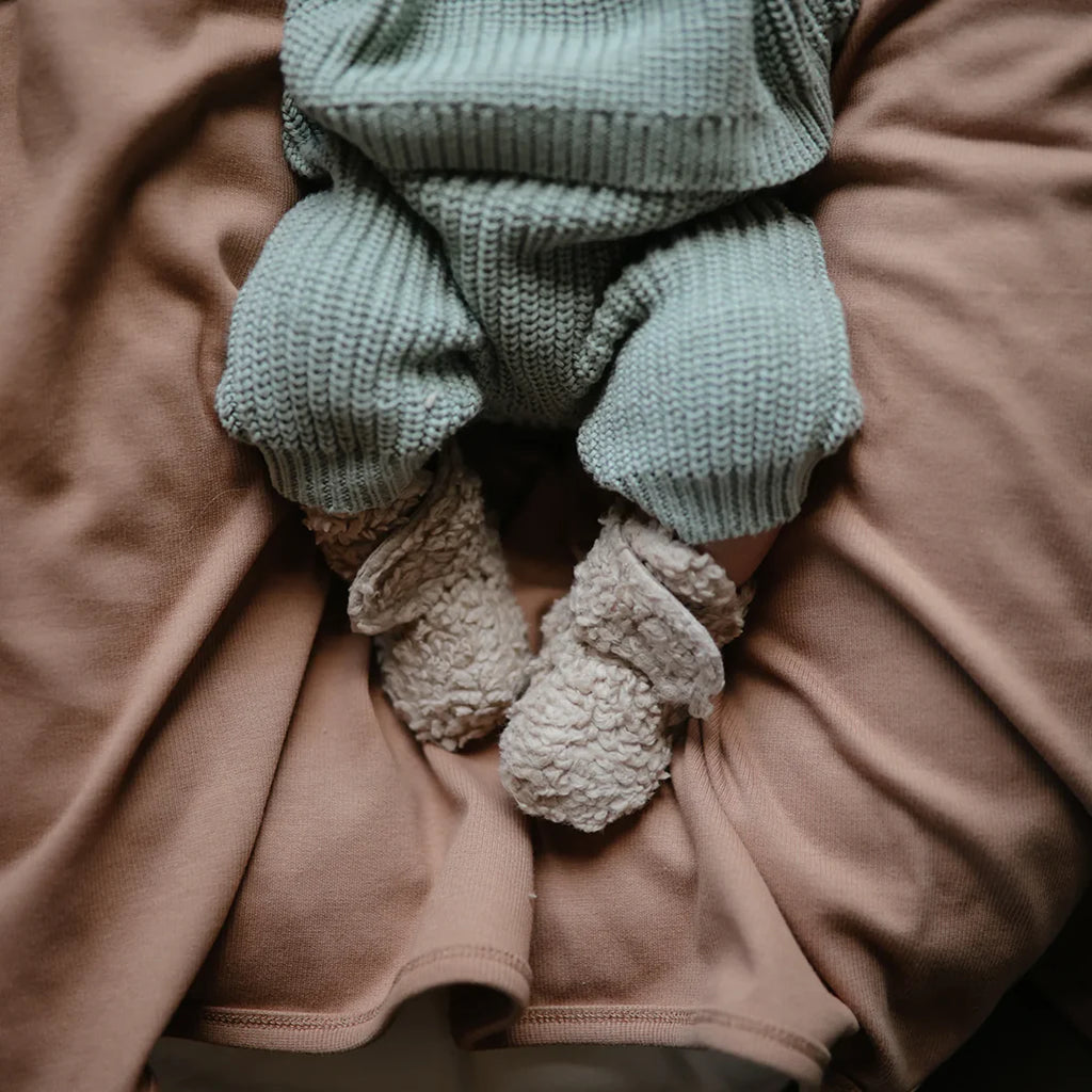 infant in fleece booties mushie