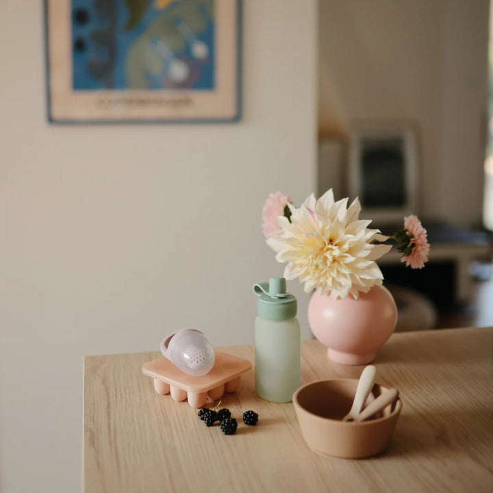 Lifestyle image of Cambridge Blue Uppababy mushie silicone puree pouches, easy to hold for little hands.