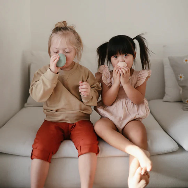 Feeding scene with Blush Uppababy mushie silicone starter cup, made from food grade silicone.