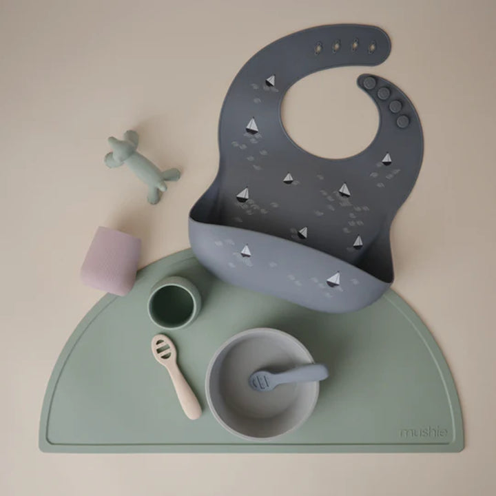 Child holding Blush Uppababy mushie silicone starter cup, easy to hold for little hands.