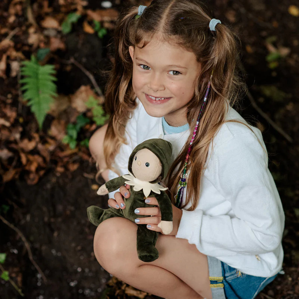 eight year old girl holding olli ella dinky dinkums percy pine doll in the forest 