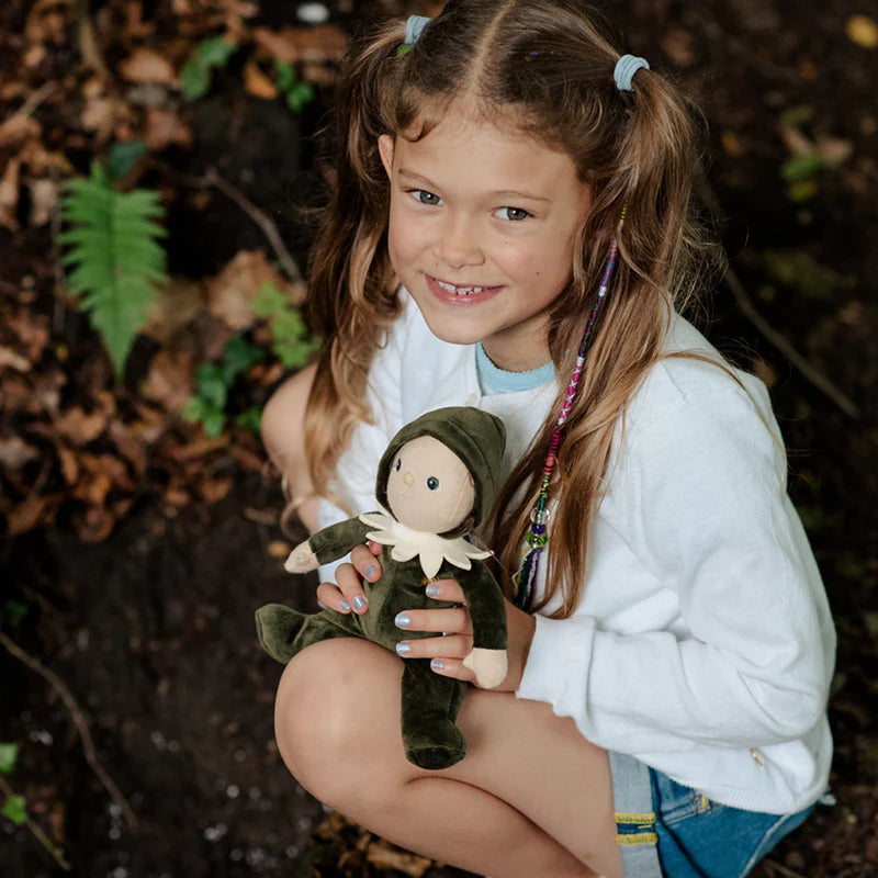eight year old girl holding olli ella dinky dinkums percy pine doll in the forest 