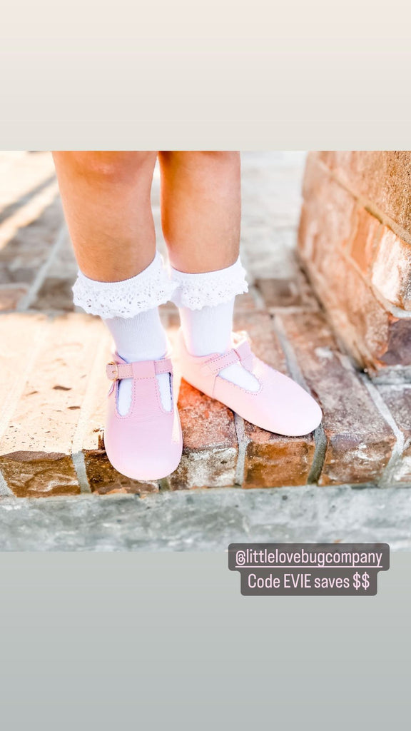 A pair of pink leather t-bar Little Love Bug shoes being worn.