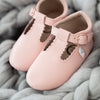 Little Love Bug organic leather t-bar shoes in the color pink on a blanket.