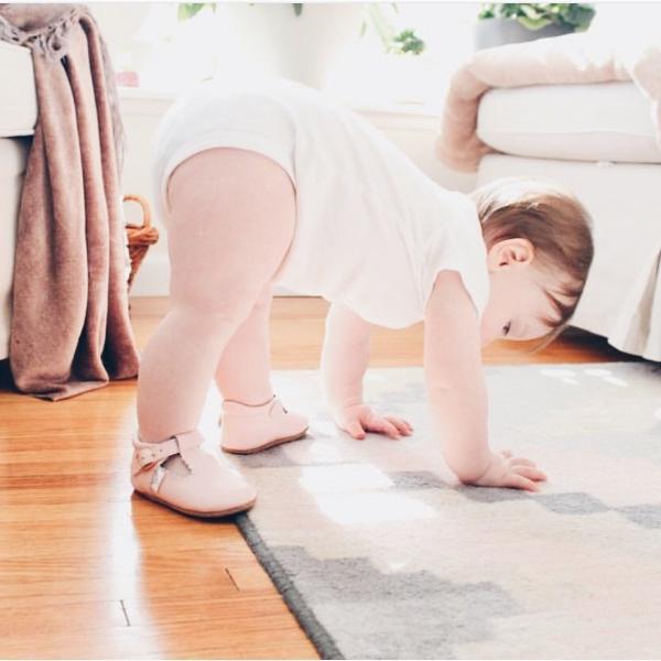 Baby wearing a pair of Little Love Bug Company's pink leather anti-slip t-bar shoes.