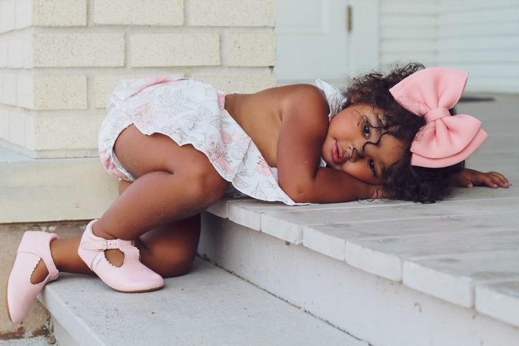 Toddler with pair of pink Little Love Bug toddler leather shoes.