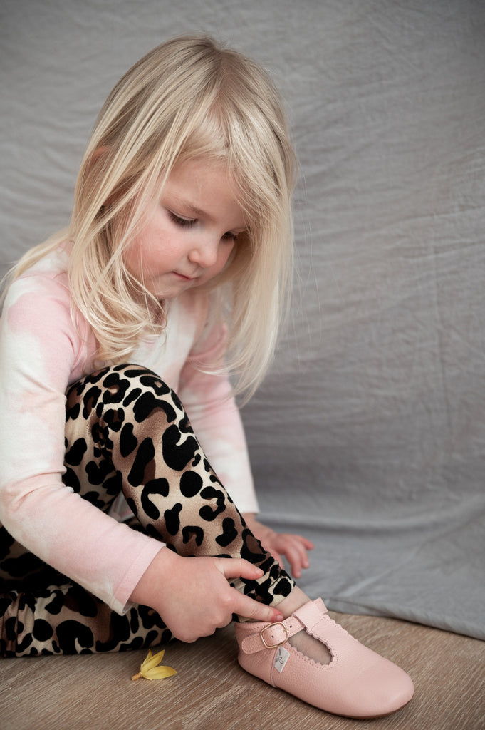 Girl wearing Little Love Bug pink, organic leather t-bar shoes.