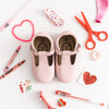 Pink leather Little Love Bug t-bar shoes sitting on a white background.