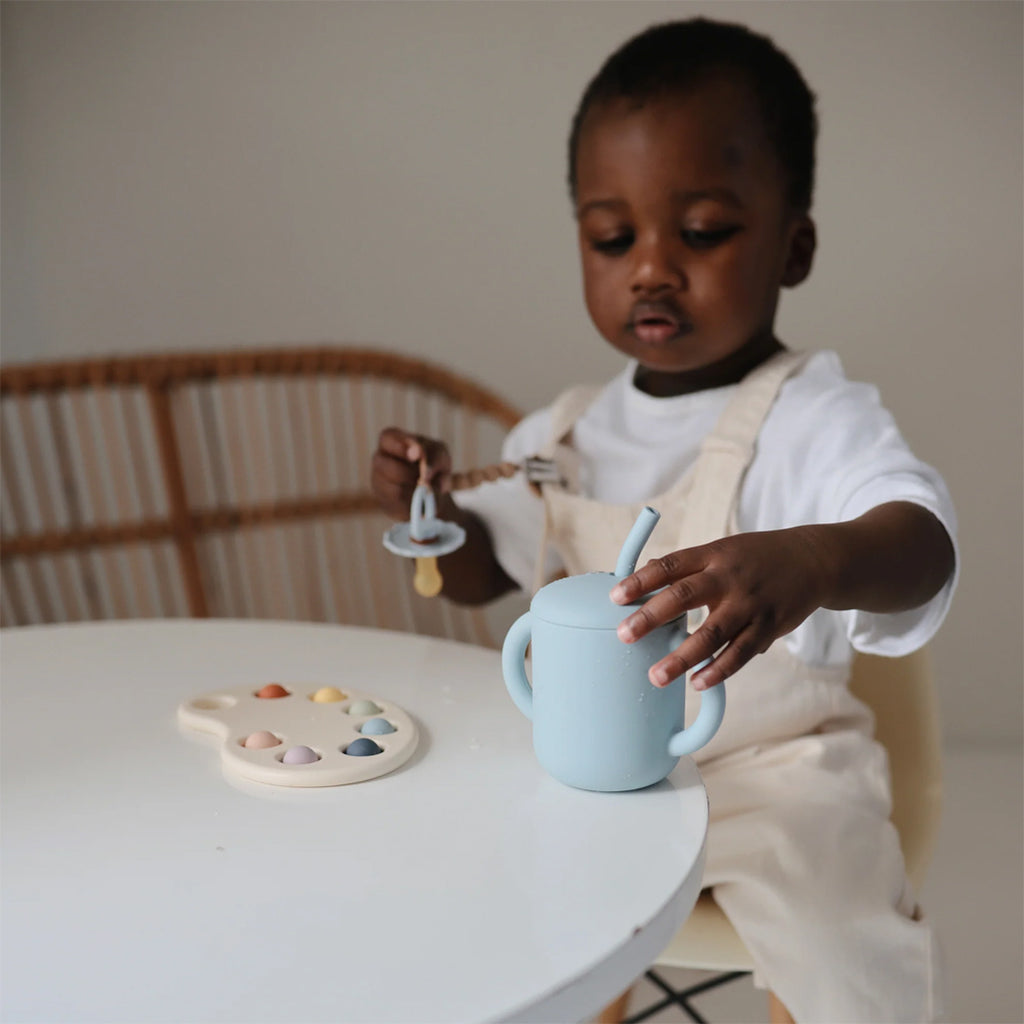 Child using powder blue training cup.