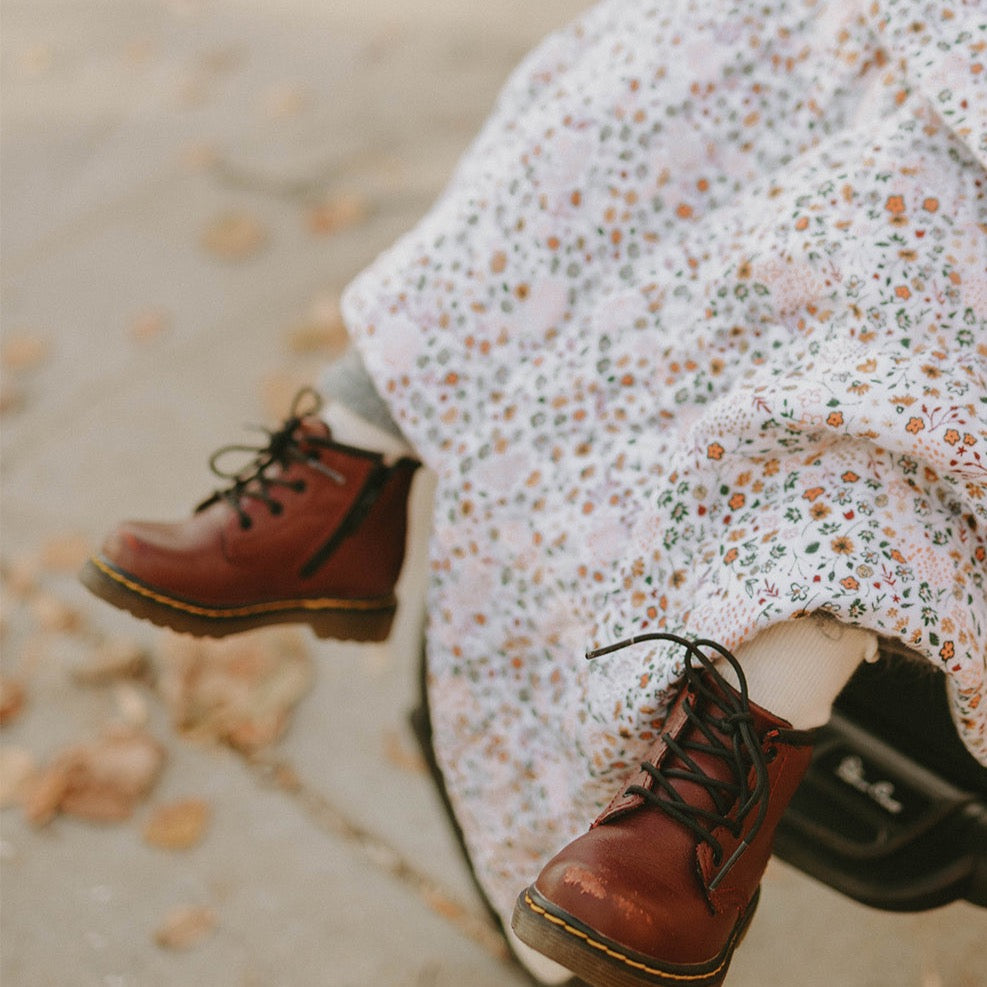 Little Unicorn Cotton Muslin Baby Quilt - Pressed Petals draped across a chair, offering softness and style with muslin baby blankets.
