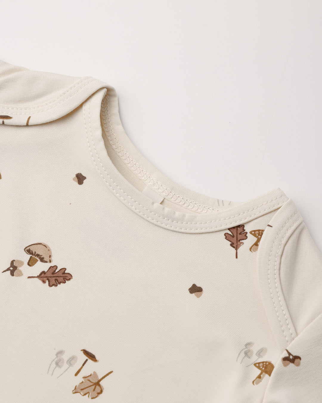 Detail of the Woodland print, Quincy Mae bamboo baby gown and hat set on natural