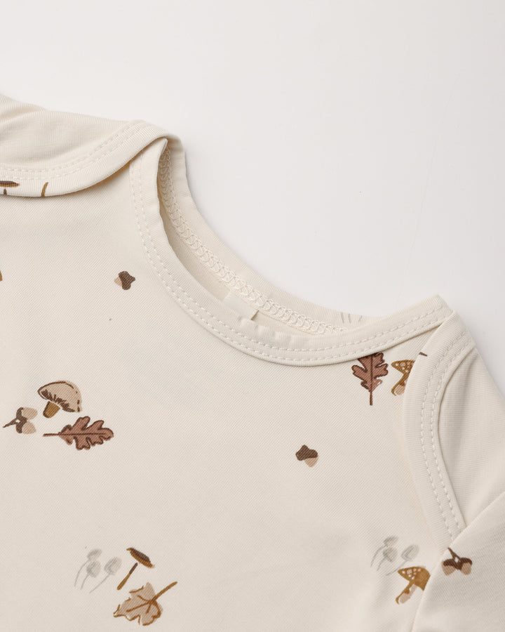 Detail of the Woodland print, Quincy Mae bamboo baby gown and hat set on natural