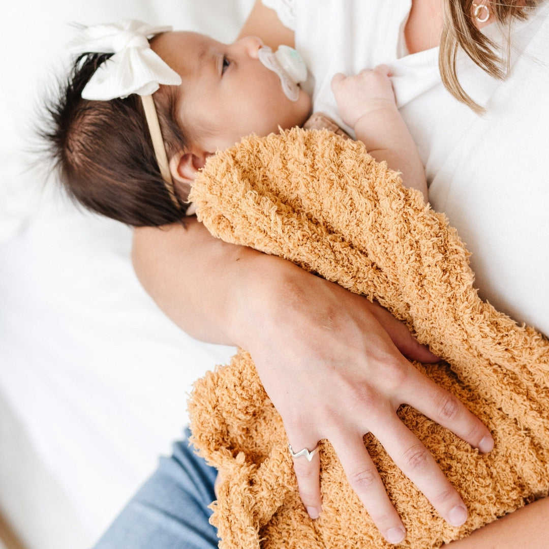 Golden showcases SaranoniÕs Ribbed BAMBONI¨ Mini Blanket, crafted for gentle comfort and perfect as a baby boy blanket.