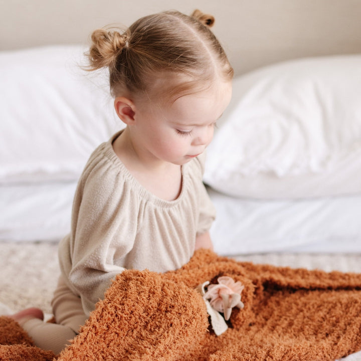 The Saranoni Ribbed BAMBONI¨ Mini Blanket in Ginger adds elegance and warmth, making it a cherished baby girl blanket.