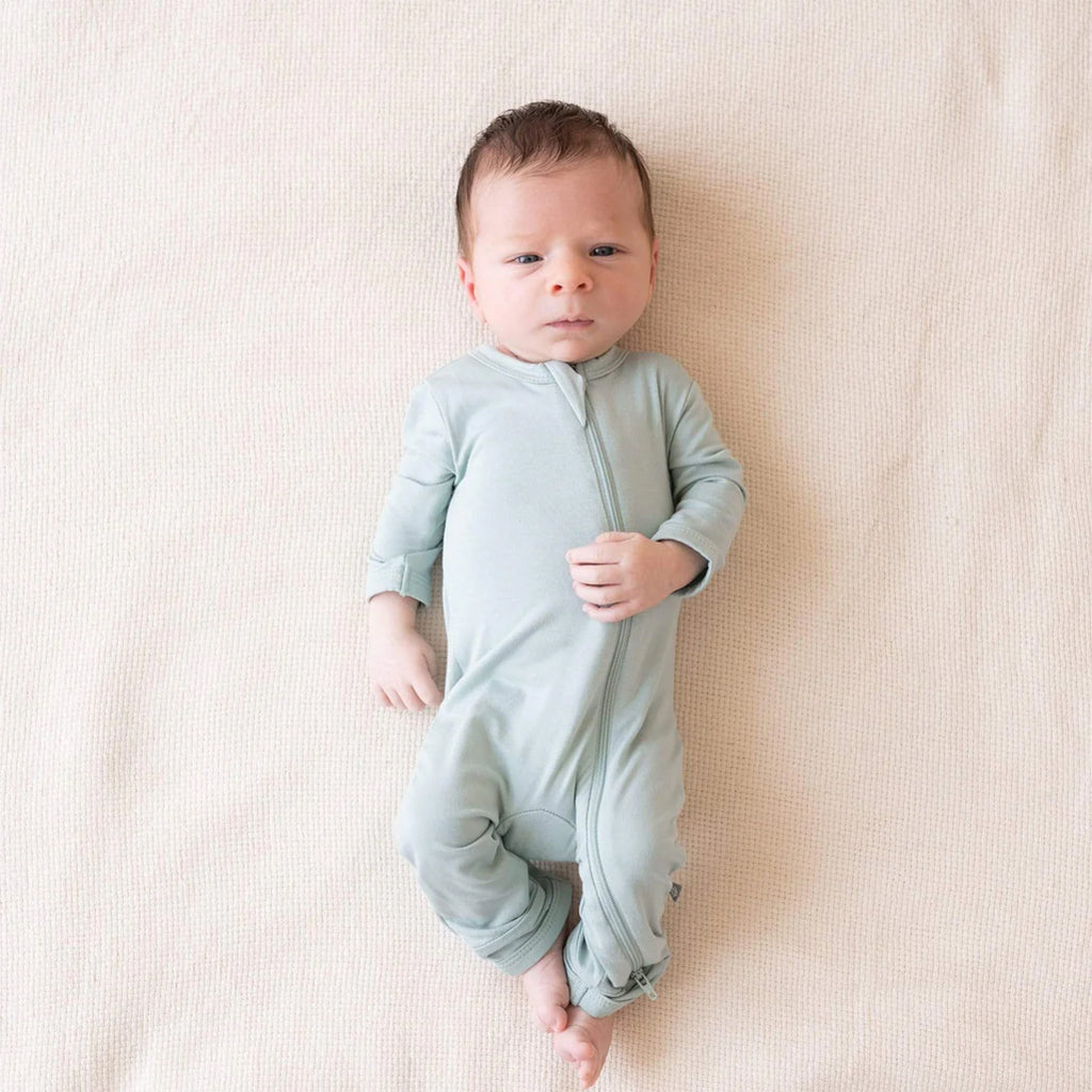 Newborn baby wearing the cozy Kyte Zipper Romper in the shade Sage.